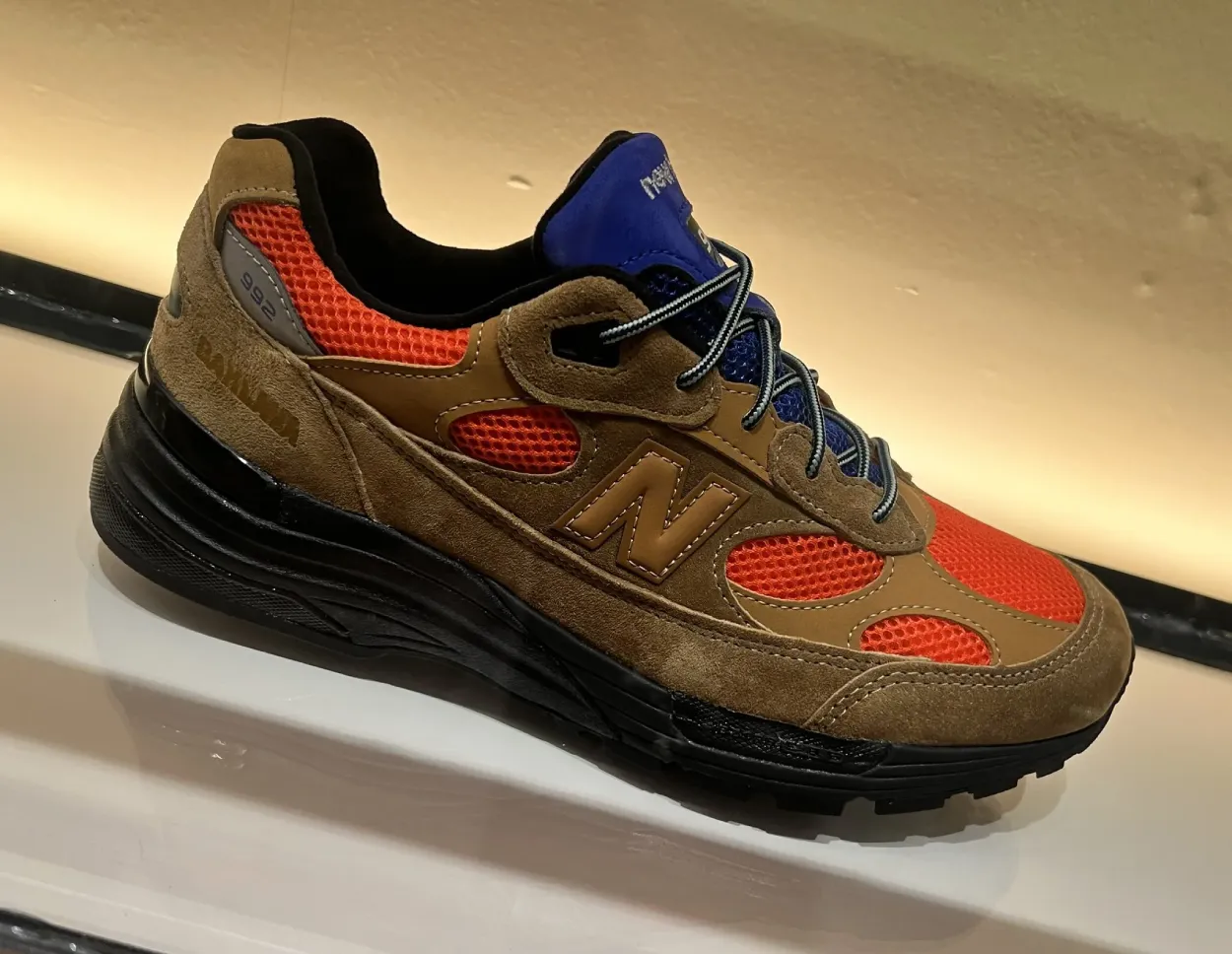 Seitenansicht des Action Bronson x New Balance 992 mit braunem Wildleder, orangefarbenem Mesh und blauer Zunge.