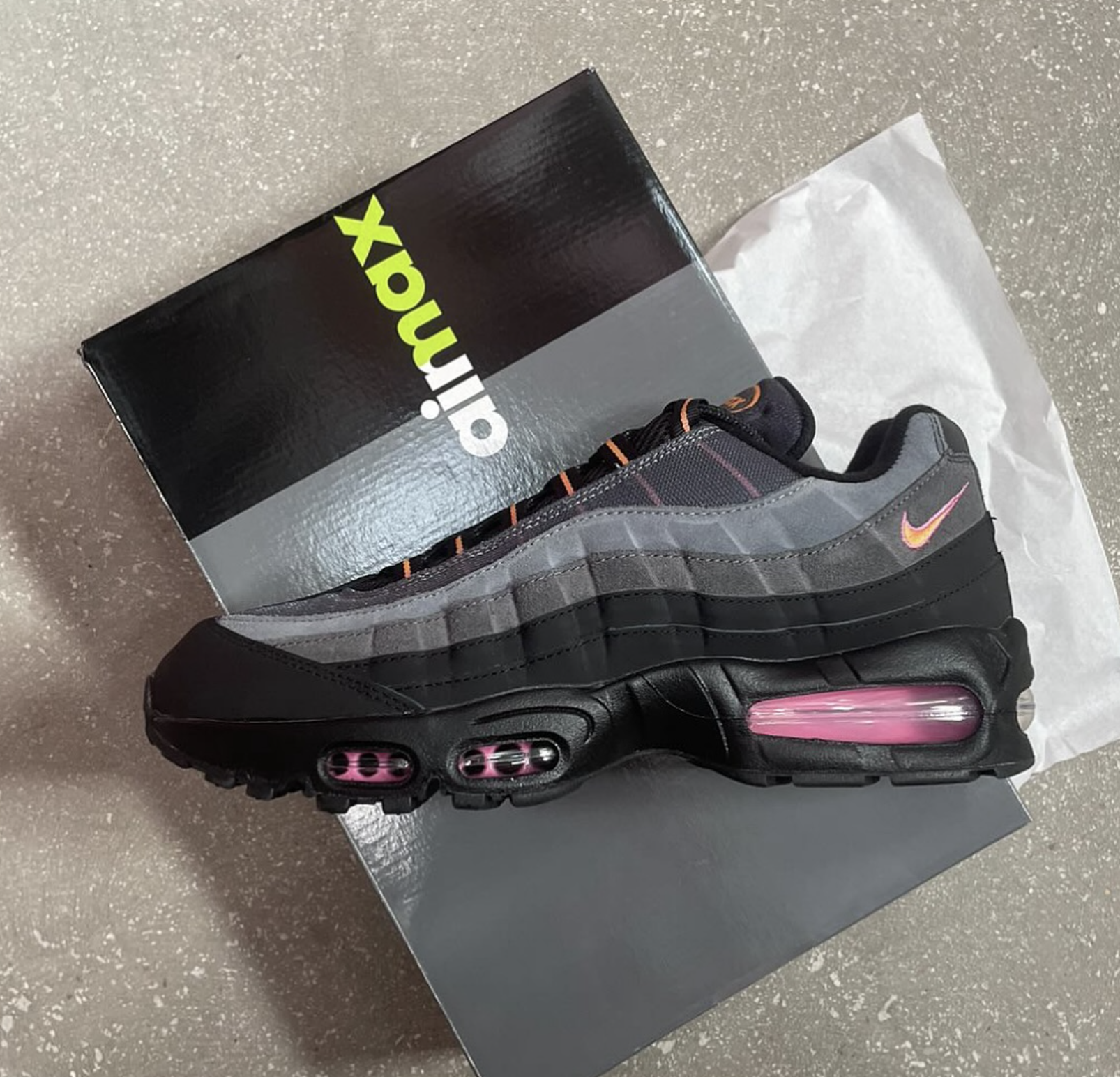 The Nike Air Max 95 “Sundial” resting on its black and lime green branded Air Max box, showing off its gradient design and vibrant details.